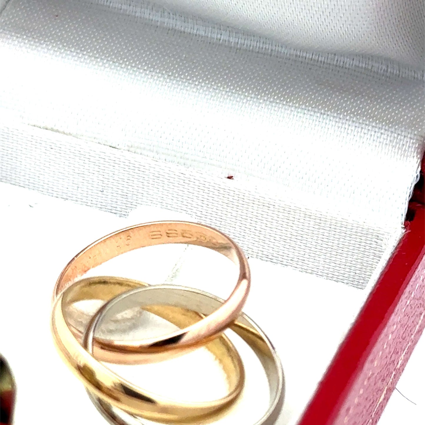 Dreifarbiger Cartier Trinity Ring aus Gold mit Zertifikat, detailreiche Design und polierte Oberfläche, auf weißem Hintergrund.